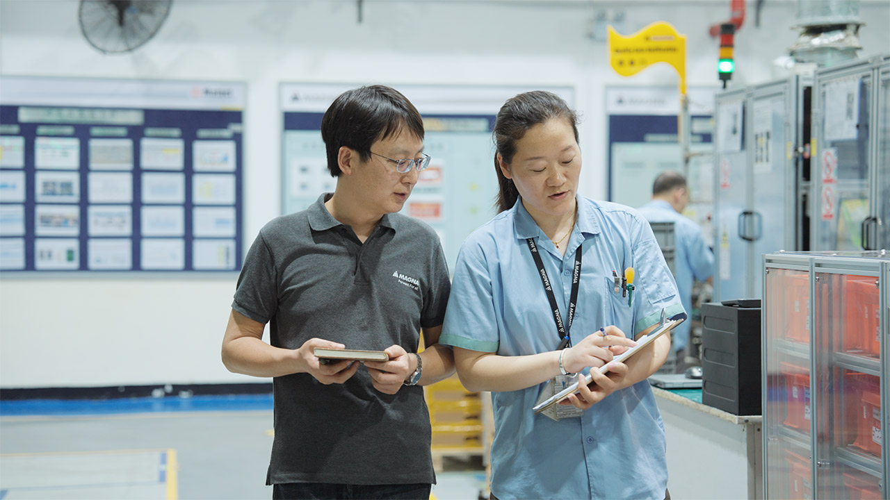 Two people looking at a clipboard standing in a manufacturing facility