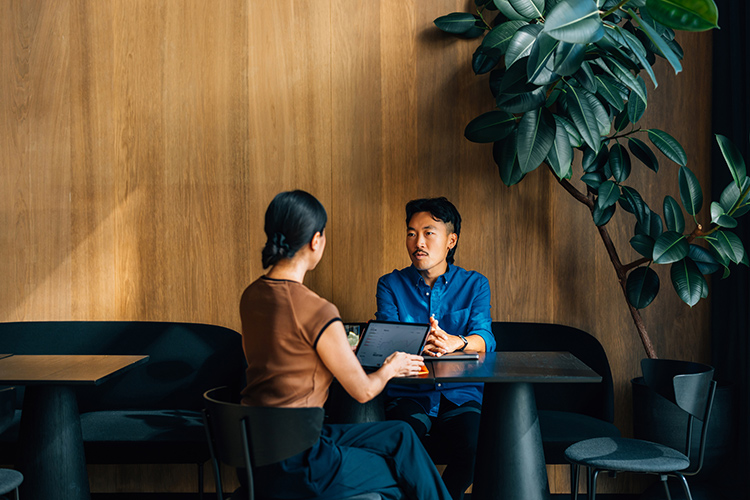 Two people sitting at a table having a discussion in an office environment