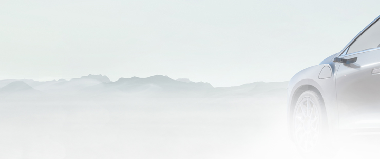 Front driver side of grey vehicle with fog and mountain range in background