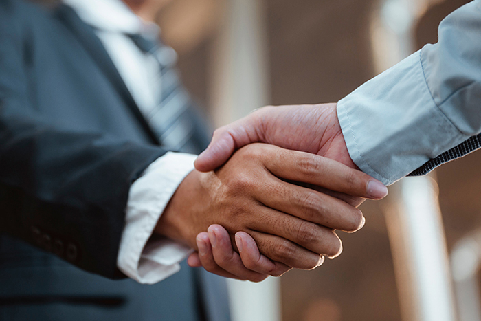 Zwei Personen geben sich zur Begrüßung oder Vereinbarung die Hand