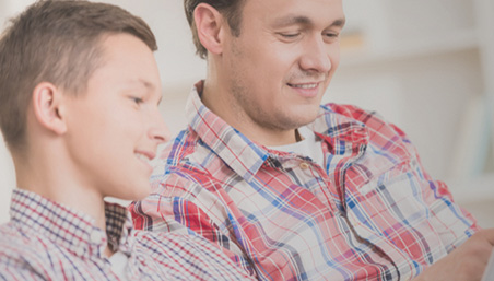 Father and son smiling while looking at a screen