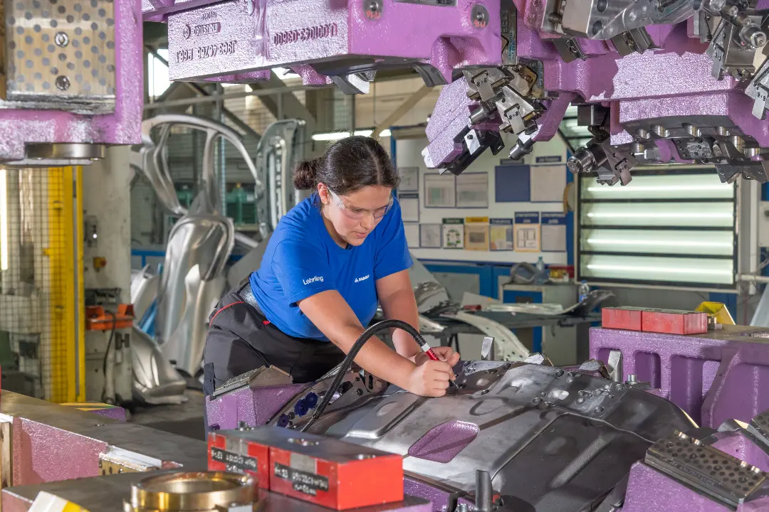 Female technician working on a large metal part in a manufacturing facility