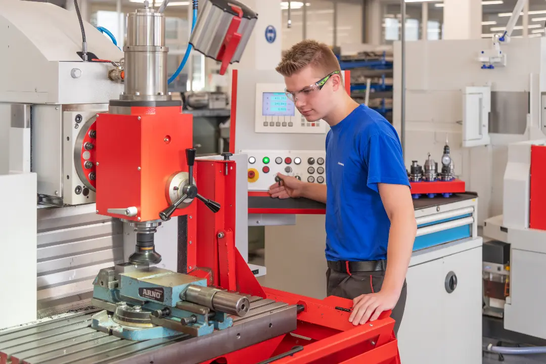 Young technician operating a milling machine in a workshop