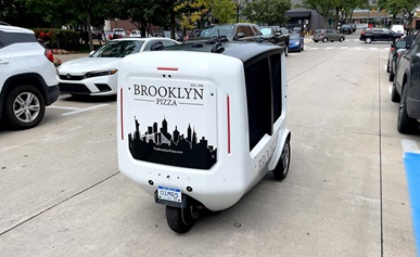 Two people standing in front of a building with electric two-wheelers.