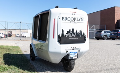 Two people standing in front of a building with electric two-wheelers.