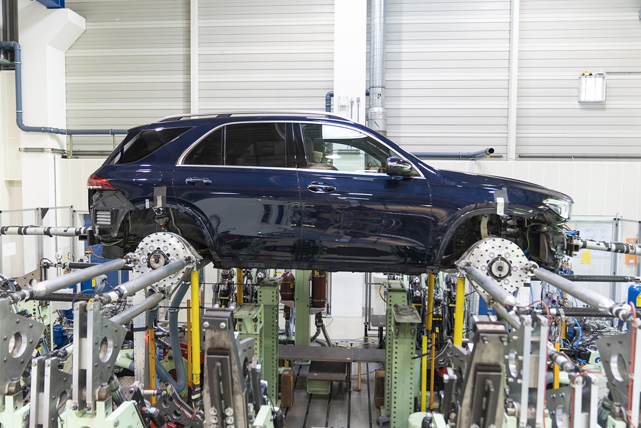 A car mounted on hydraulic test rigs inside a laboratory for vehicle performance and durability testing