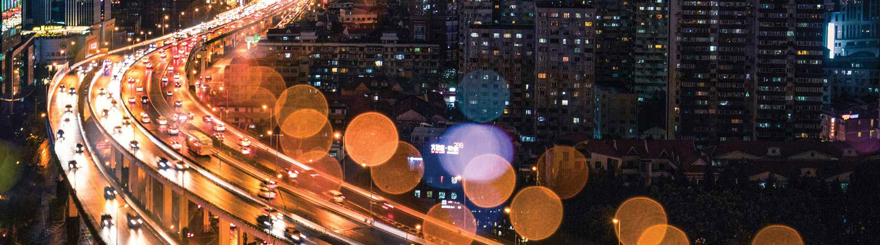 A highway at night with many cars and buildings in background