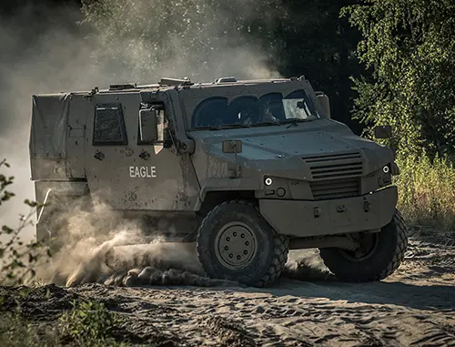 Large vehicle driving along a dirt road in a wooded area