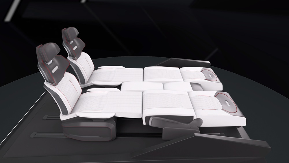 Two car seats reclined fully into a flat, bed-like position. The seats are white with dark headrests, set against a sleek, dark interior.