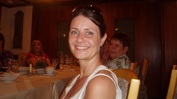 Maria Kennedy smiling and sitting at table in a restaurant with a group of people