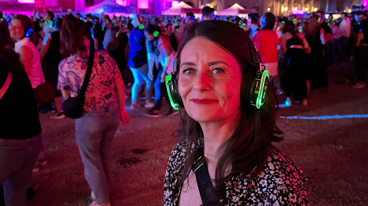 Maria Kennedy at a festival smiling and wearing green glowing headphones