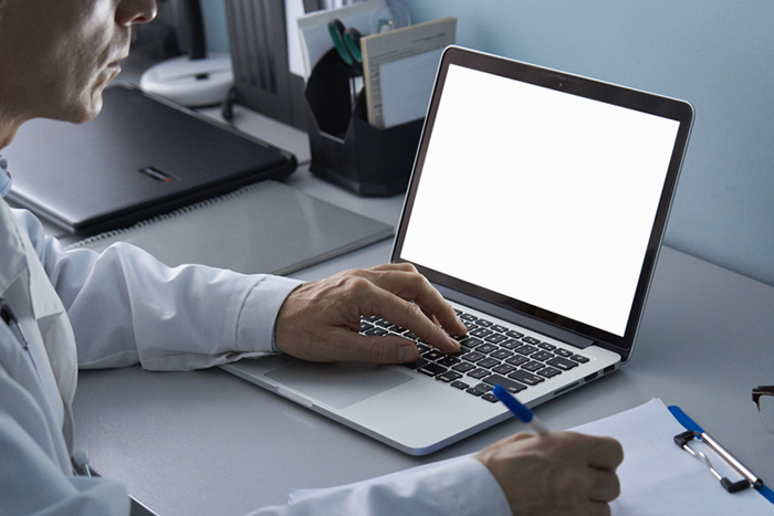 Person im Laborkittel, die einen Laptop mit leerem Bildschirm benutzt